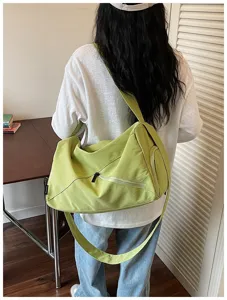 Vue arrière détaillée d'un sac de sport vert clair avec fermeture éclair diagonale et sangle.