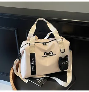 Grand sac de voyage de sport en beige avec joli pendentif chat et bandoulière réglable.