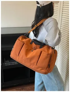 Large capacity orange travel duffel bag with multiple exterior pockets and shoulder strap.