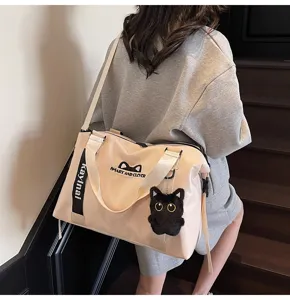 Vue détaillée d'un sac de voyage beige élégant avec pendentif chat et bandoulière.