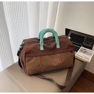 Vue détaillée du grand sac de voyage avec corps marron et poignées élégantes turquoise.