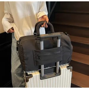 Vue détaillée du grand sac de voyage noir avec sangle pour valise et tissu imperméable.
