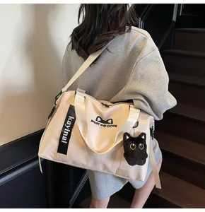 Vue détaillée du grand sac de voyage cabas avec adorable pendentif chat et bandoulière confortable.