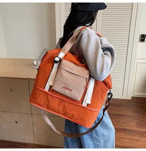 Vista detallada de la gran bolsa de viaje naranja con bolsillo delantero y correa.