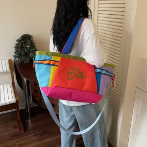 Color-block canvas tote bag detail, featuring multi-color patchwork and wide shoulder strap.