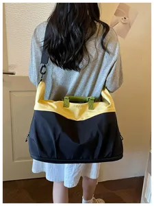 Gran bolsa de viaje deportiva con diseño de bloques de color negro y amarillo, ideal para escapadas.