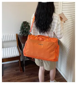 Vue détaillée du grand sac de voyage orange souple montrant le style de port au dos.