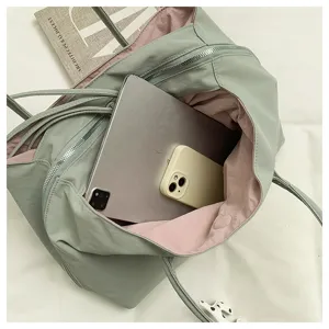 Detail shot showing interior capacity of the green tote bag holding tablet and phone securely.