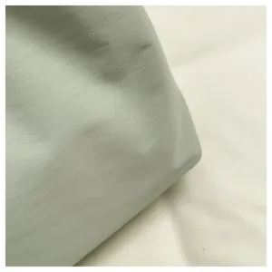 Close-up detail of light green tote bag fabric texture, showcasing soft synthetic material.