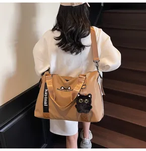Vue détaillée du grand sac de voyage de sport avec joli pendentif chat en peluche et broderie.