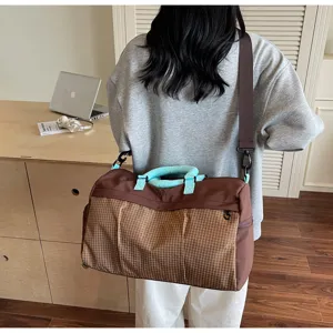 Vue détaillée d'un sac de voyage marron à carreaux spacieux avec des poignées bleues élégantes.