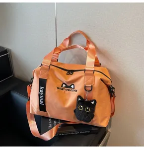 Détail du sac de voyage de sport orange avec charm peluche chat mignon et sangle