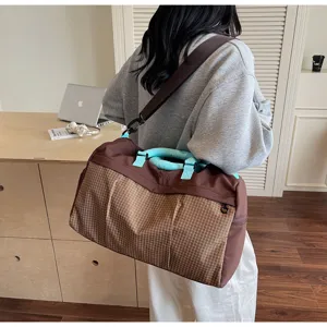 Vue détaillée d'un grand sac de voyage avec motif à carreaux et poignées bleues.