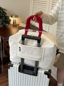 Grote canvas reistas met handvatten in het rood en trolleysleuf voor korte reizen.
