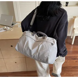 Vue détaillée du grand sac de voyage, porté élégant sur l'épaule dans un décor moderne.