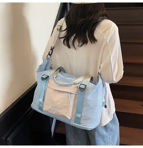 Vista detallada de una bolsa de viaje grande en azul y beige con correa ajustable.