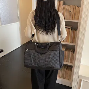 Detailed shot showing the large capacity black travel duffel bag worn on shoulder, indoor view.
