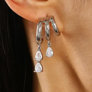 Close-up view of silver hoop earrings featuring sparkling teardrop-shaped zircon pendants.