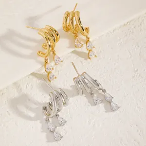 Close-up of gold and silver multi-layered C-hoop earrings with pear-shaped rhinestone drops.