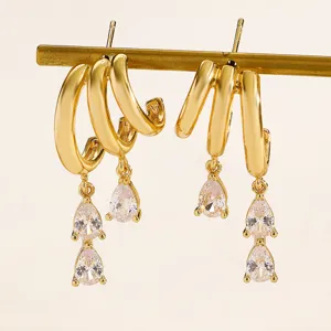 Close-up of elegant gold hoop earrings with sparkling teardrop zircon pendants on stand
