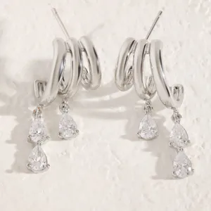 Close-up of silver-toned multi-layered C-hoop earrings with pear-cut rhinestone tassels.