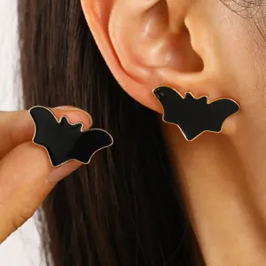 Detalle de pendientes de murciélago en esmalte negro para un look de joyería de Halloween