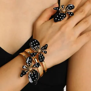 Detail des Retro-Schmucksets mit gepunkteten Blumen, goldenem Armreif und passendem Ring.