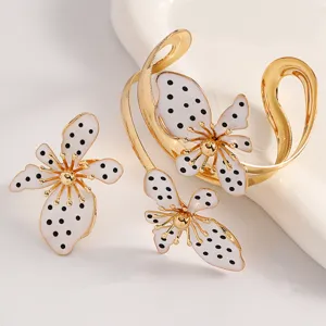 Nahaufnahme des Retro-Schmucksets mit gepunkteten Blumen, goldenem Armreif und Ring