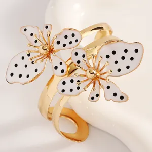 Detailansicht eines Retro-Goldarmbands mit großen weißen Blumen und schwarzen Punkten.