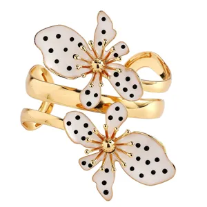 Detailansicht eines goldenen Manschettenarmbands mit schwarz-weißen gepunkteten Blumenmotiven