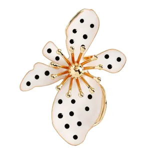 Nahaufnahme eines weißen Emaille-Blumenrings mit schwarzen Punkten und Goldakzenten