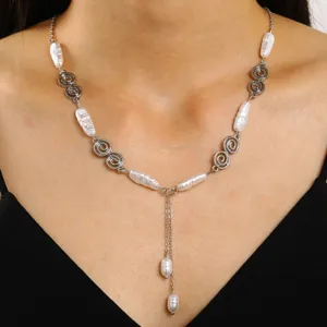 Macro view of a vintage Y-shaped necklace featuring baroque pearls and silver spiral links