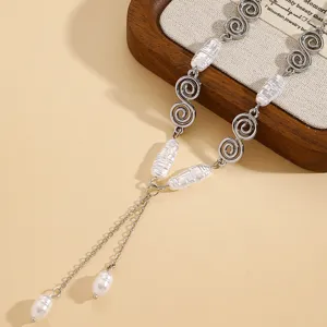 Close-up of vintage silver necklace with spiral motifs and baroque pearls.