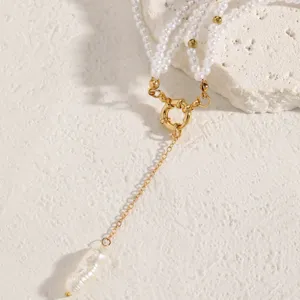 Detail of gold chain necklace with multi-layer pearls and a baroque pearl drop pendant