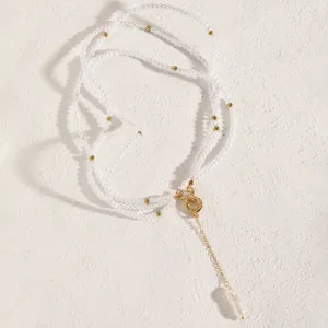 Detail view of a long multi-layer pearl necklace with golden OT buckle and baroque pearl.