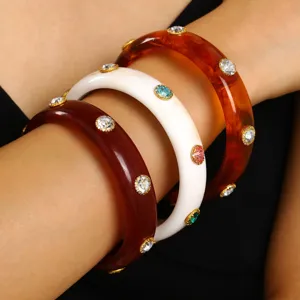 Close-up view of three stacked retro acrylic chunky bangles with colorful rhinestone details