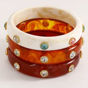 Stack of retro wide acrylic bangles featuring colorful crystals and marble textures