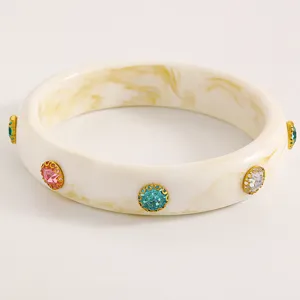 Detailed view of vintage cream acrylic bangle with colorful rhinestone embellishments