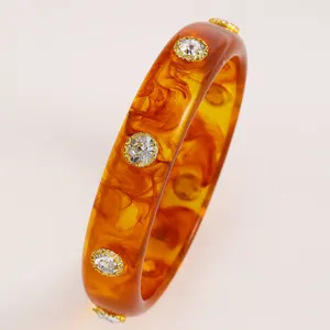 Close-up of vintage amber acrylic bangle with sparkling crystal accents