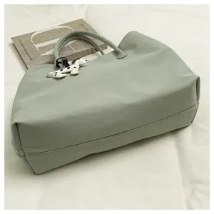 Detail view of light green tote bag interior structure and cute dog charm pendant accessory.