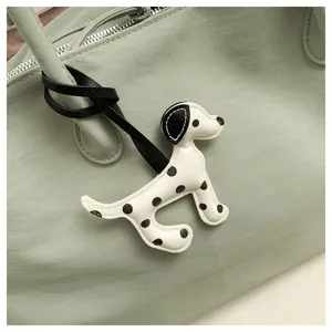 Detailed view of green tote bag with cute dalmatian puppy leather charm and black strap.