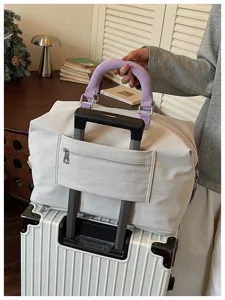 Grande borsa da viaggio con fascia per valigia e manico viola per trasporto agevole.