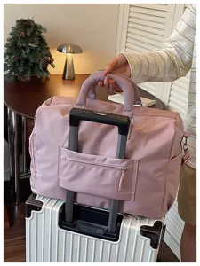 Vue détaillée du grand sac de voyage rose avec une sangle pratique sur la valise.