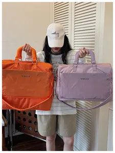Vue détaillée montrant de grands sacs de voyage en orange et violet avec des poignées.