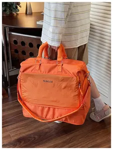 Détail de sac de voyage orange, grande capacité en nylon, poche avant pour une utilisation facile.