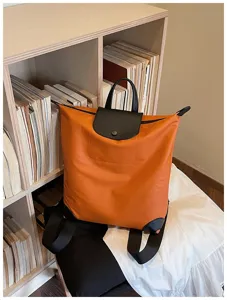 Elegante zaino da pendolare arancione con patta in pelle nera per uso quotidiano e viaggi.