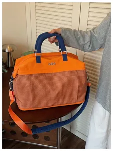 Grande borsa da viaggio in arancione e blu con motivo a griglia, capiente e pratica.