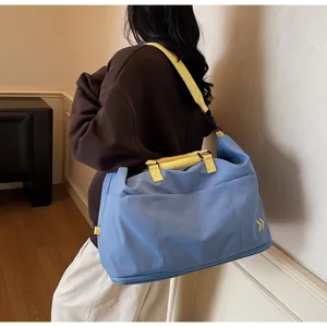 Detail view of large capacity travel duffel bag, featuring blue body and yellow straps for fitness.