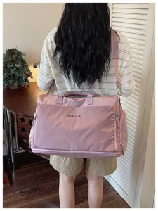 Sac de voyage rose avec bandoulière et poche avant pour les courts voyages et le sport.