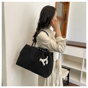 Details view of the black canvas tote bag featuring double shoulder straps and a cute dog charm.